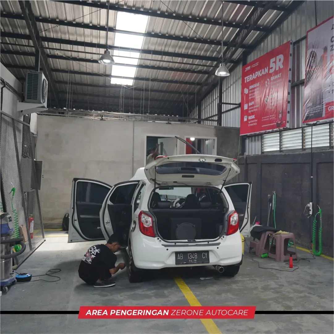 Mobil dengan pintu terbuka sedang dikerjakan di area pengeringan workshop Jogja